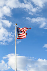 Celebrate independence day, 4th of July, with American flag flying against a sunny blue sky with white puffy clouds, Grand Canyon National Park, Arizona
