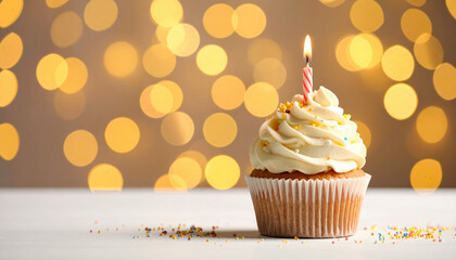 Birthday cupcake with lit candle and cream frosting on white table with golden bokeh lights background, festive celebration and joyful mood