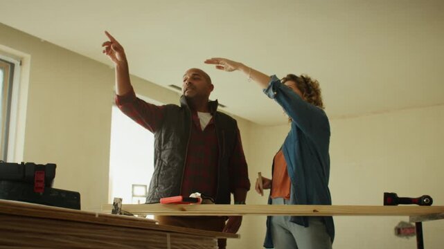 A middle-aged man and woman discuss home renovation plans in a landscape, wide shot video. They point and gesture, envisioning their dream home.