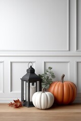 Stylish indoor fall decor with a black lantern, large orange and white pumpkins, eucalyptus leaves, and dried autumn foliage against a white wall with molding. Elegant seasonal interior composition