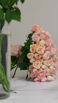 Florist forms a bouquet on the table from pink bush rose Christie