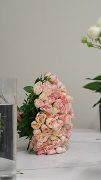Florist forms a bouquet on the table from pink bush rose Christie