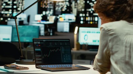 Female analyst monitoring and documenting global market progress trends, forex data in office after hours. Applying finance insights and economic analysis for organizational growth. Camera B. - Powered by Adobe