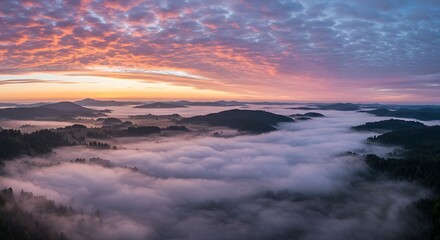 Panoramic view of mountains covered in mist during sunrise or sunset