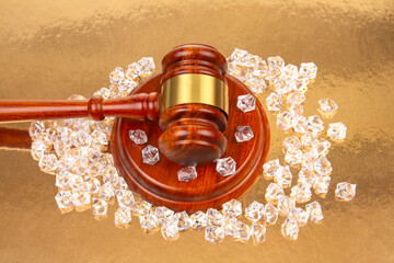 Legal gavel surrounded by sparkling gems on a reflective golden surface