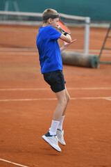 Obraz premium Young boy playing tennis on real court outdoor