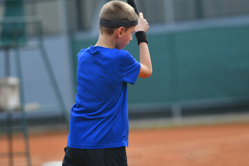 Young boy playing tennis on real court outdoor