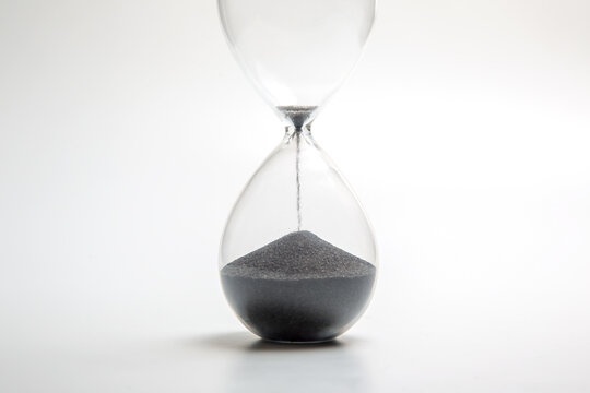 Hourglass filled with black sand highlighting the passage of time in a minimalistic design