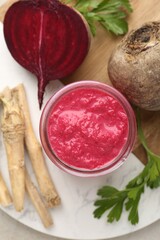 Tasty horseradish sauce with beetroot, parsley, roots and vegetables on light table, top view