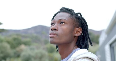 Noticing movement above, African American man turning head and smiling on balcony, copy space - Powered by Adobe
