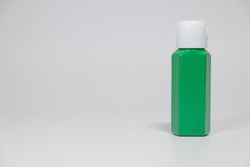 Green plastic bottle with white cap on plain background