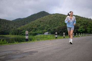 Obraz premium Young woman running outdoors in nature with headphones