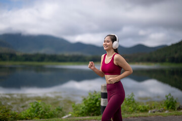 Woman wearing headphones running outdoors by lake
