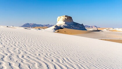 Rippled white sand dunes and chalk rock formations in the famous White Desert National Park, Egypt, under a clear blue sky.