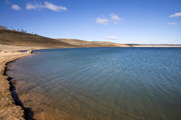 Tree-lined hills roll down to the clear waters of Lake Eucumbene in the Snowy Mountains of NSW, Australia. This alpine lake is regarded as a premier trout fishing location.