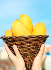 Fresh Tropical Mango Fruits in Wicker Basket - Yunnan Hawksbill Variety Against Blue Sky