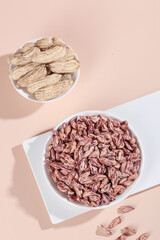 Colorful Peanuts and Striped Kernels in White Bowls on Pink Background - Natural Agricultural Produce Display
