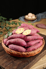 Fresh Sweet Potatoes in Wicker Basket on Rustic Wood Table with Organic Eggs