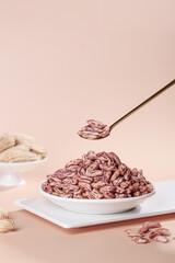 Colorful Dried Peanuts Being Scooped with Golden Spoon on Pink Background