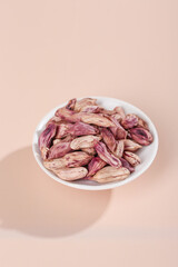 Colorful Raw Peanuts in Shell in White Bowl on Pink Background - Healthy Snack Food