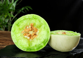 Fresh Honeydew Melon Halves with Green Flesh and Seeds on Slate Surface