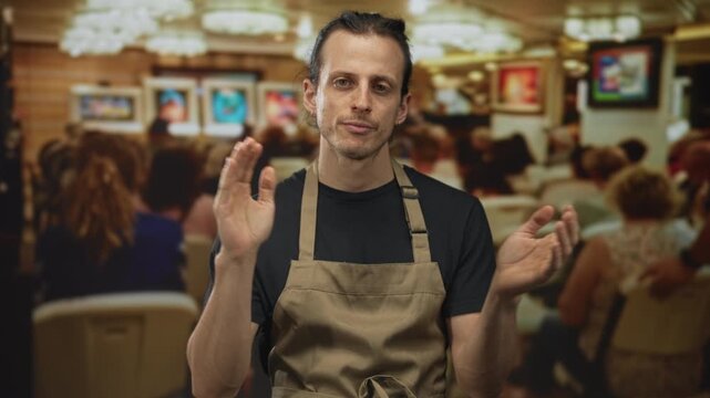 Man clapping hands while seated in a building gallery during an indoor art talk; thoughtful reflection creativity.