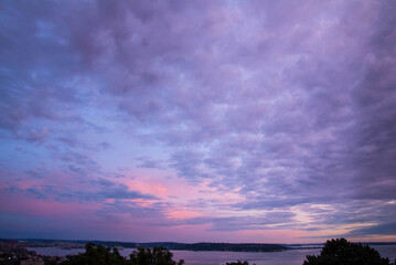 View of Seattle skyline under a dramatic purple, blue and pink sky at dusk interrupted by clouds. Taken from Kerry Park, a city public park in Seattle, Washington State.
