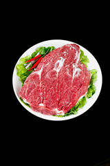 Fresh Raw Beef Steak Cuts with Marbled Texture on White Plate with Lettuce Garnish