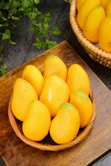 Fresh Tainong Mango Fruit Closeup in Wicker Basket on Wooden Board