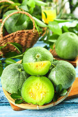 Fresh Shandong Emerald Melons with Yellow Centers in Bamboo Basket on White Wooden Surface