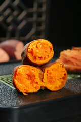 Fresh Roasted Sweet Potatoes Cut in Half on Wooden Board Showing Orange Flesh