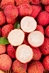 Fresh Hainan Lychee Fruits Cut Open Showing White Flesh and Red Textured Skin on Bamboo Background