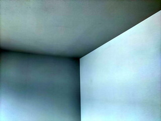 部屋の角を捉えた抽象的な写真で白い壁と濃い灰色の壁そして天井との境目が作り出すシャープな線と色のグラデーションが特徴的である