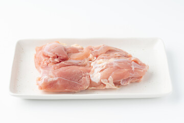 白背景にお皿に載せた生の鶏もも肉