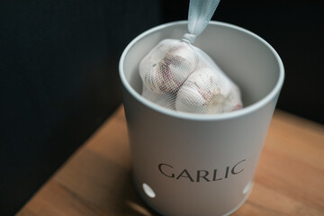 Bagged garlic bulbs in canister on kitchen bench