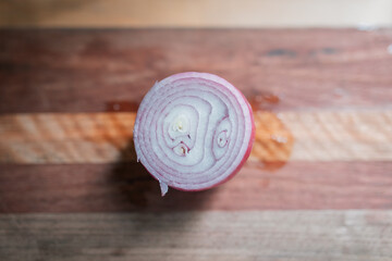 Top down view of cut red onion on wooden chopping board