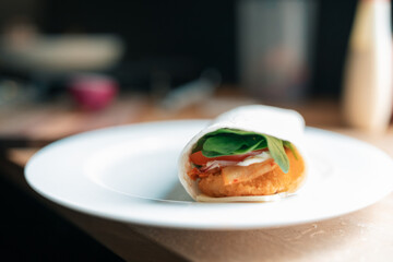Chicken wrap on kitchen bench with tomato, spinach and kimchi
