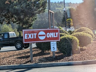 Fototapeta premium Crescent City, CA – September 10, 2025 Large red “EXIT ONLY” sign and “SPEED LIMIT 5 MPH” sign near a parking lot in Crescent City, CA. Traffic control and safet