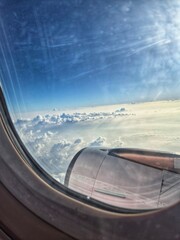 Portrait of bright clouds during the day as seen from inside an airplane