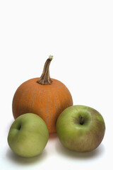 An orange pumpkin and two green apples on a white background.  The picture is vertical.  There is ample blank space for text. 