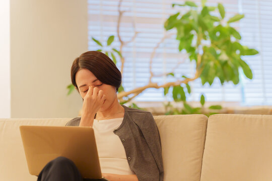 夜パソコンで仕事する眼精疲労の女性