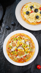 Delicious Italian Pizzas with Fresh Fruit and Vegetable Toppings on Dark Slate Background