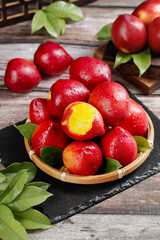 Fresh Red Nectarines with Yellow Flesh in Wicker Basket on Rustic Wood Background