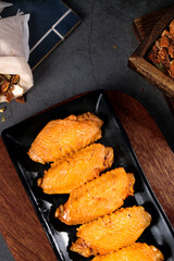 Golden Cooked Marinated Chicken Wings on Black Plate with Rustic Kitchen Setting