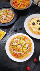 Fresh Baked Italian Pizza Variety with Cheese and Vegetable Toppings on Dark Slate Surface