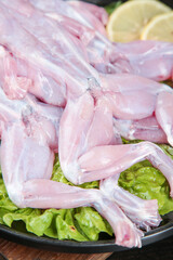 Fresh Raw Frog Legs in Cooking Pot with Lettuce and Lemon - Gourmet Amphibian Cuisine Preparation