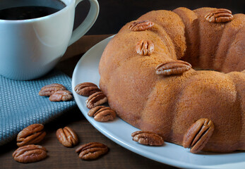 pastel de nueces con nueces encima una servilleta azul y una taza con cafe negro por un lado con angulo de vista y fondo oscuro
