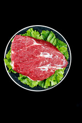 Fresh Raw Beef Brisket Cut on Plate with Lettuce Garnish