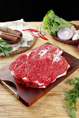 Raw Beef Steaks on Cutting Board with Fresh Vegetables and Cooking Ingredients