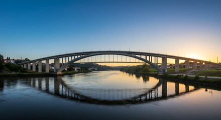 Obraz premium Arch bridge over river with clear sky at sunset reflected in water